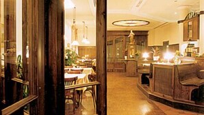 Een ruime, goed verlichte ruimte met een houten bar, een eethoek en een keuken die zichtbaar is door een open deur.