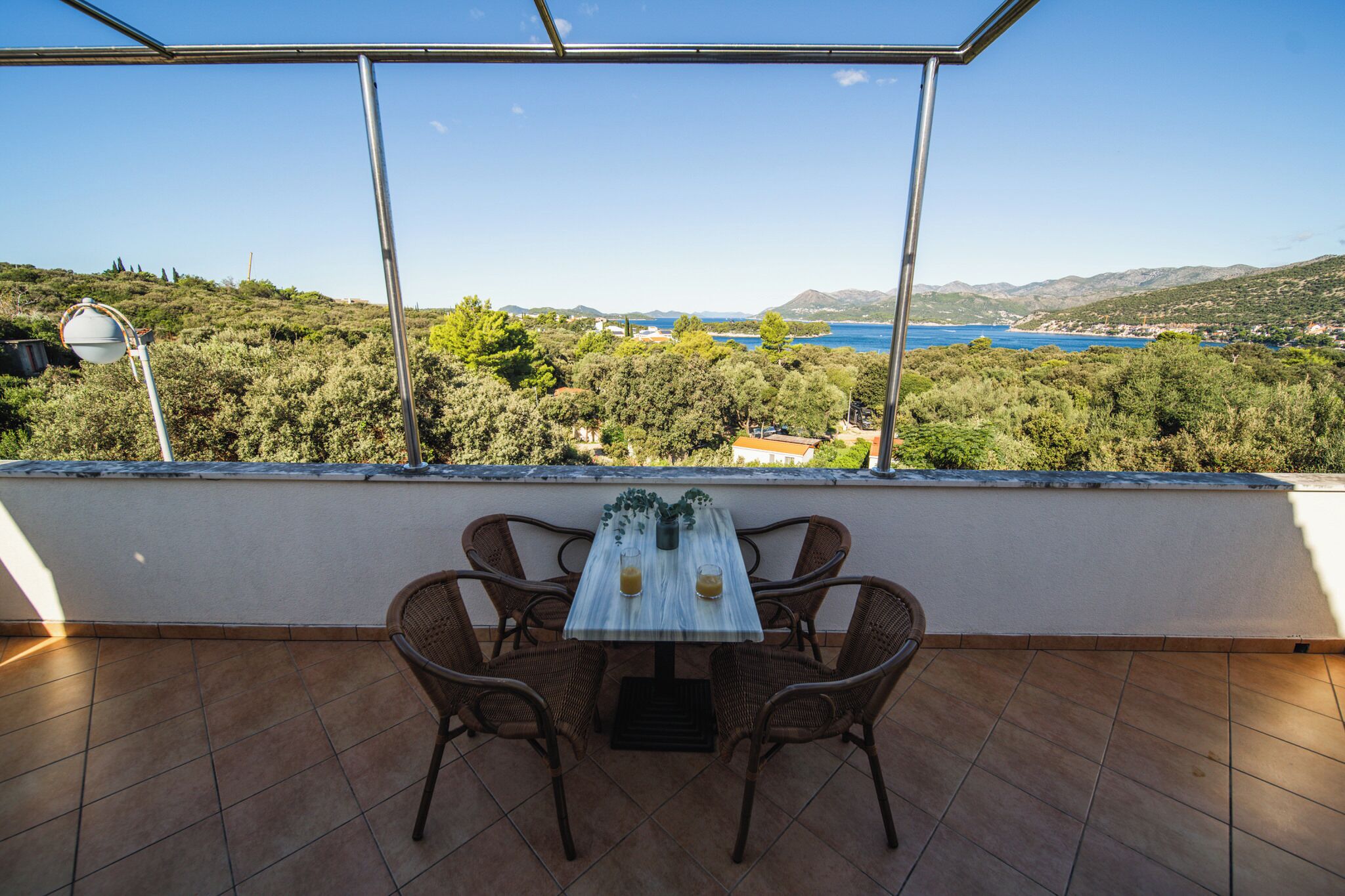 Una terraza con una mesa y sillas, con vistas a un paisaje pintoresco con árboles y una masa de agua.