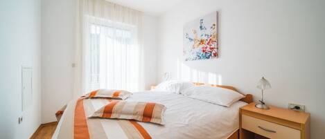 A neatly arranged bedroom with a bed, bedside table, and a wall-mounted artwork.