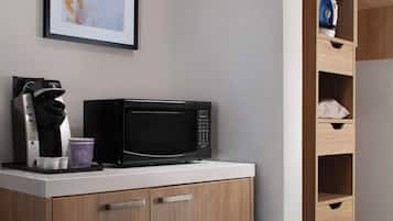 Una kitchenette equipada con microondas, cafetera y un cuadro en la pared.
