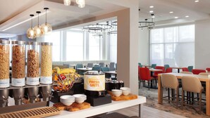 Un bufé de desayuno con diversas opciones de comida y una zona de estar con mesas y sillas.