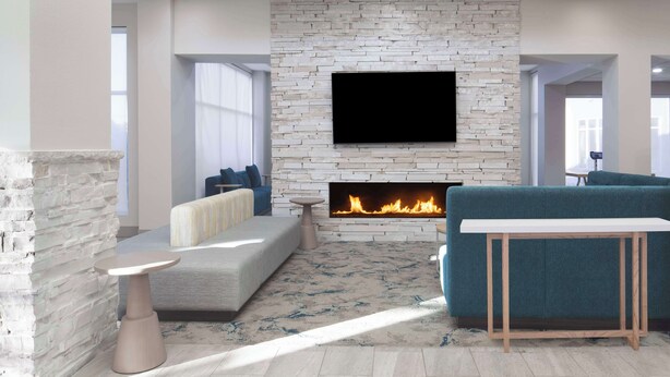 Una sala de estar moderna con pared de piedra, televisor de pantalla plana, chimenea, sofá, mesa de centro y un sofá azul.