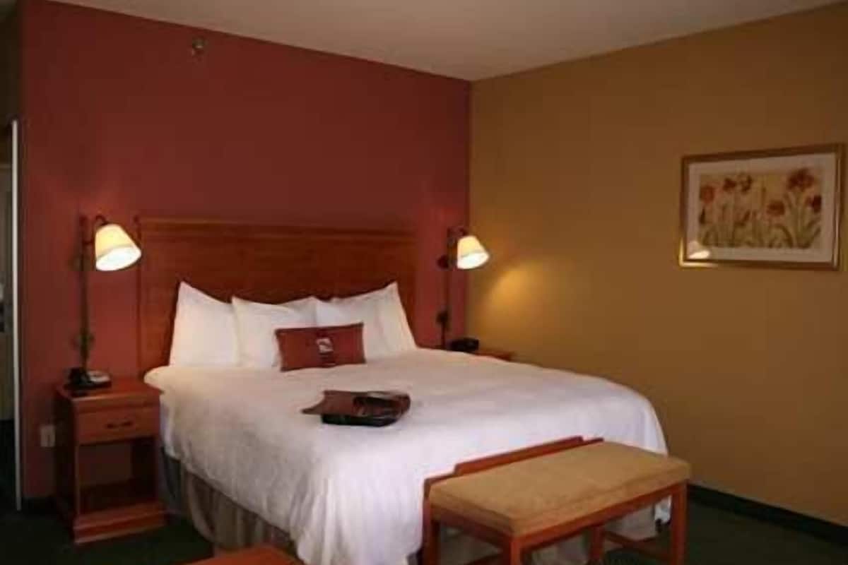 A hotel room with a bed, bedside tables, a desk, and a lamp.
