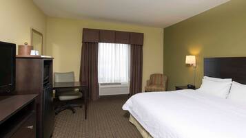 A hotel room with a bed, a desk, a chair, a television, and a window with curtains.