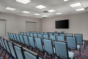 A conference room with rows of chairs, a projection screen, and a flat-screen TV on the wall. - Hampton Inn & Suites Mansfield (Mansfield)