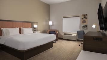 A hotel room with a large bed, a desk, a chair, a flat-screen TV, and a window.