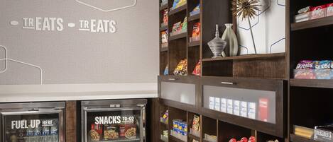 A snack bar area with shelves stocked with various snacks and a refrigerated section with drinks.