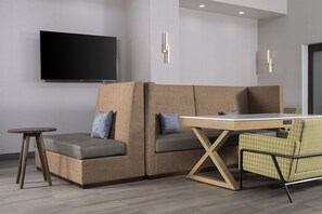 A modern hotel room with a sofa, a small table, and a television mounted on the wall. - Hampton Inn & Suites Mansfield (Mansfield)