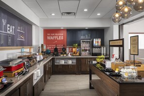 A breakfast area with a waffle station, coffee machines, and a refrigerator stocked with beverages. - Hampton Inn & Suites Mansfield (Mansfield)
