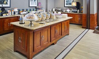 A kitchen with wooden cabinets, a granite countertop, and a breakfast bar.