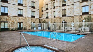 A pool area with a hot tub, surrounded by a stone building with multiple windows.