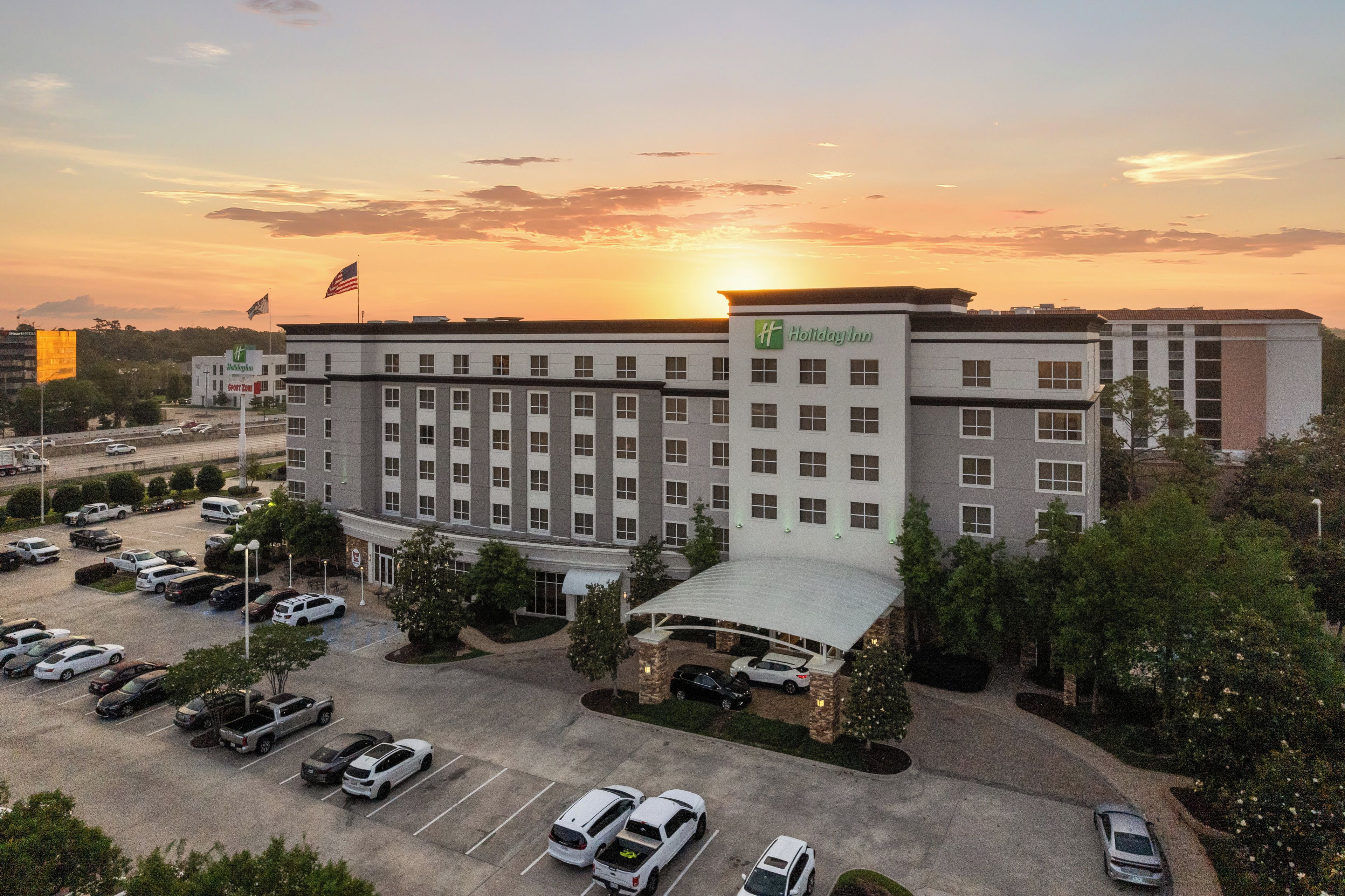 A Holiday Inn hotel with a parking lot and a sunset in the background.