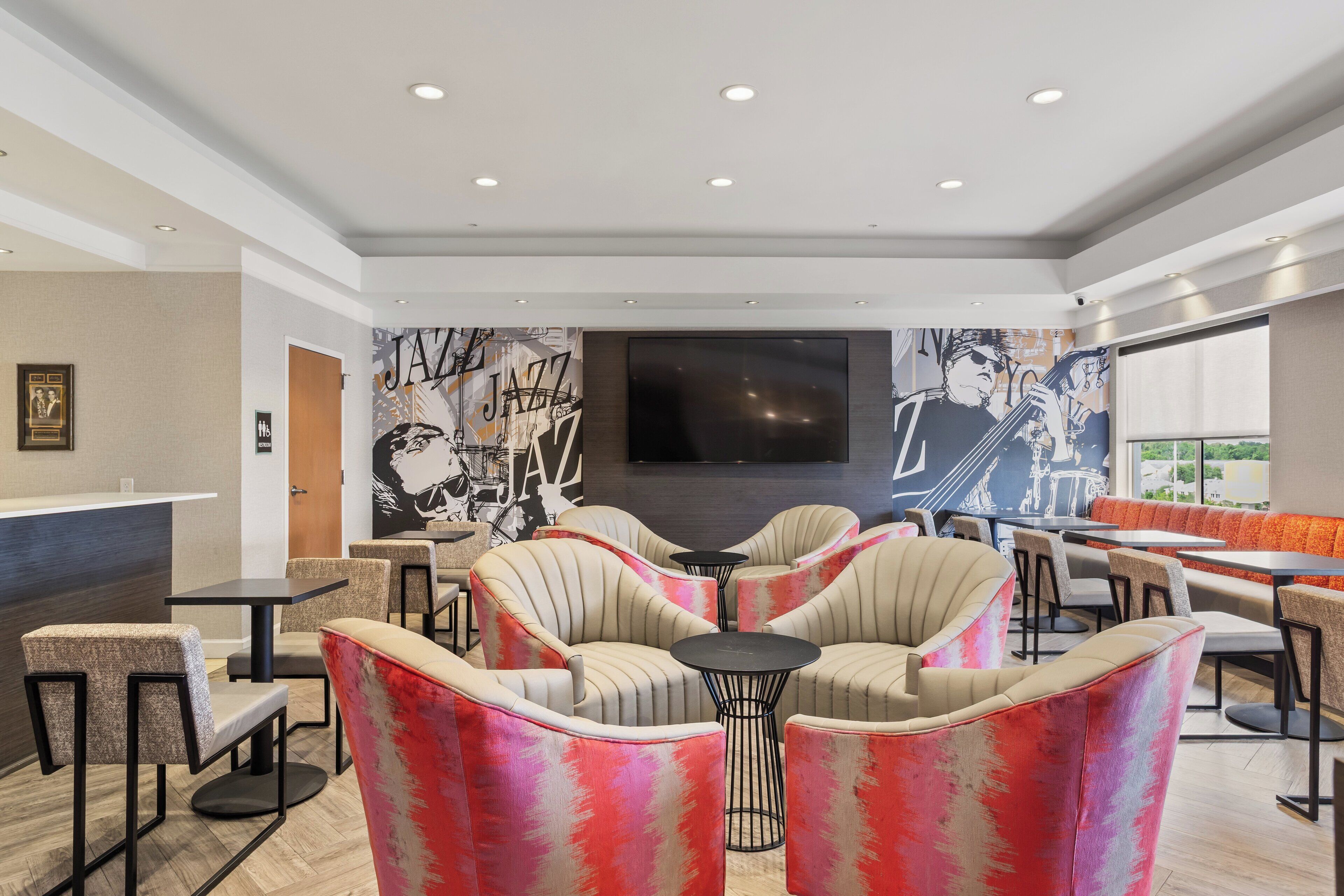 A modern lounge area with seating, a reception desk, and a large mural.