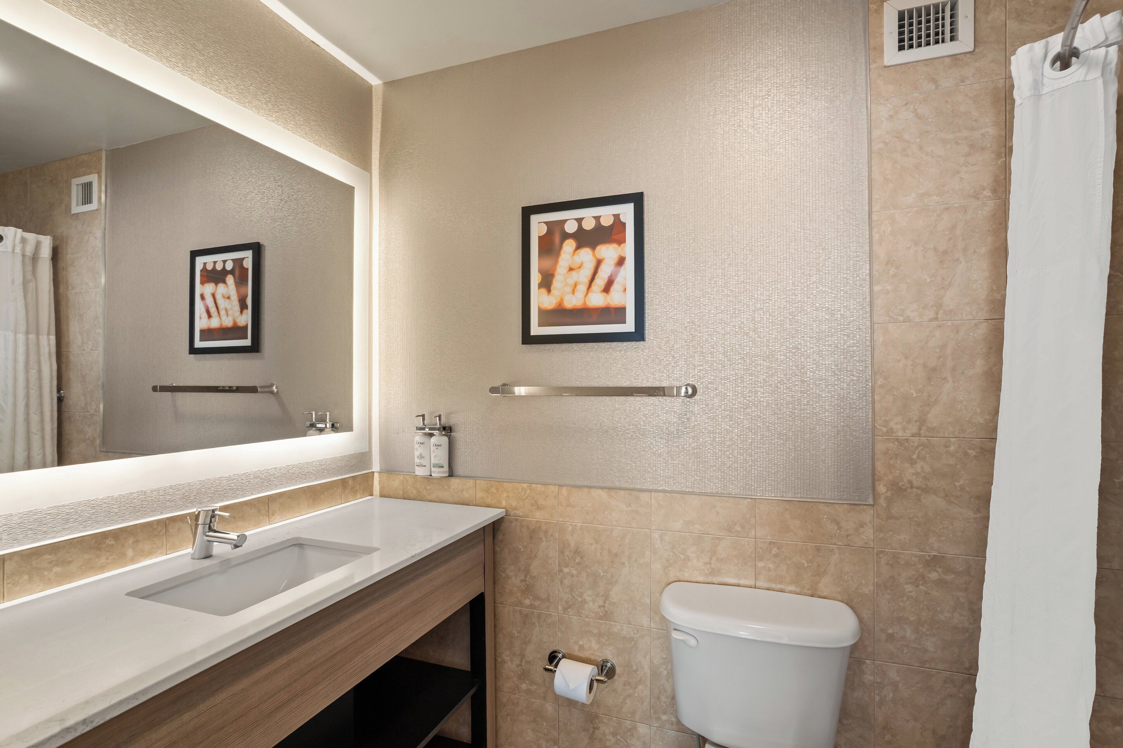 Une salle de bain équipée d’un lavabo, d’un miroir, de toilettes et d’un porte-serviettes.