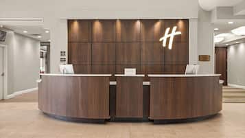 Un comptoir d’accueil avec un revêtement en bois et un grand panneau lumineux en forme de « H » au-dessus.