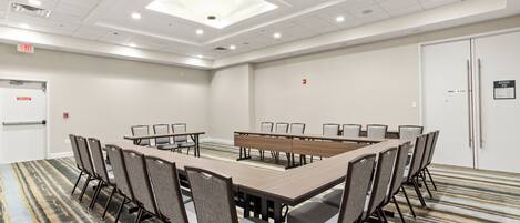 A conference room with a long table, chairs, and a patterned carpet.