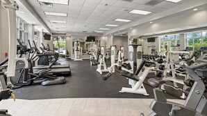 Une salle de sport équipée de tapis de course, d’appareils de musculation et d’haltères.