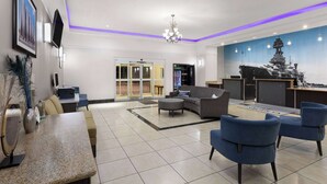 A modern lobby with a reception desk, seating area, and a large mural.