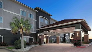 A modern hotel with a covered entrance, large windows, and a landscaped driveway.