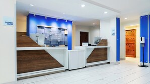 A reception area with a blue accent wall, a wooden reception desk, and a sign indicating a business center.