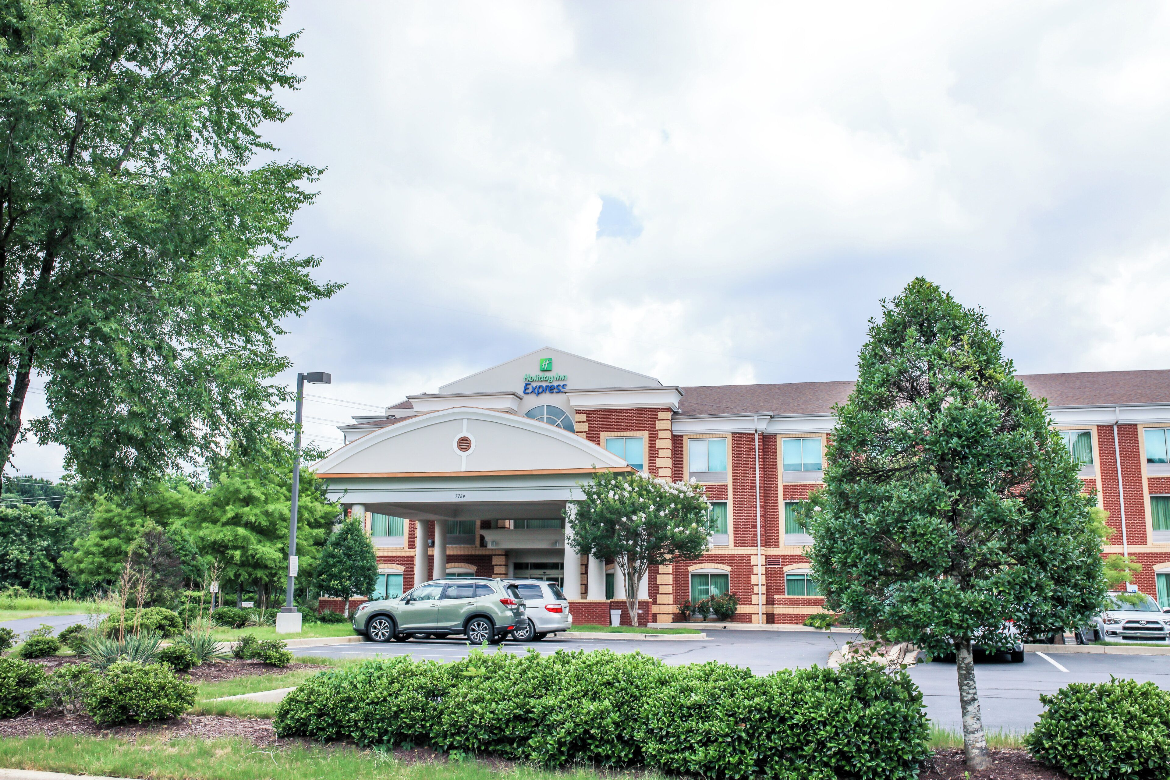 A Holiday Inn Express hotel with a brick facade, a covered entrance, and a parking lot with cars.