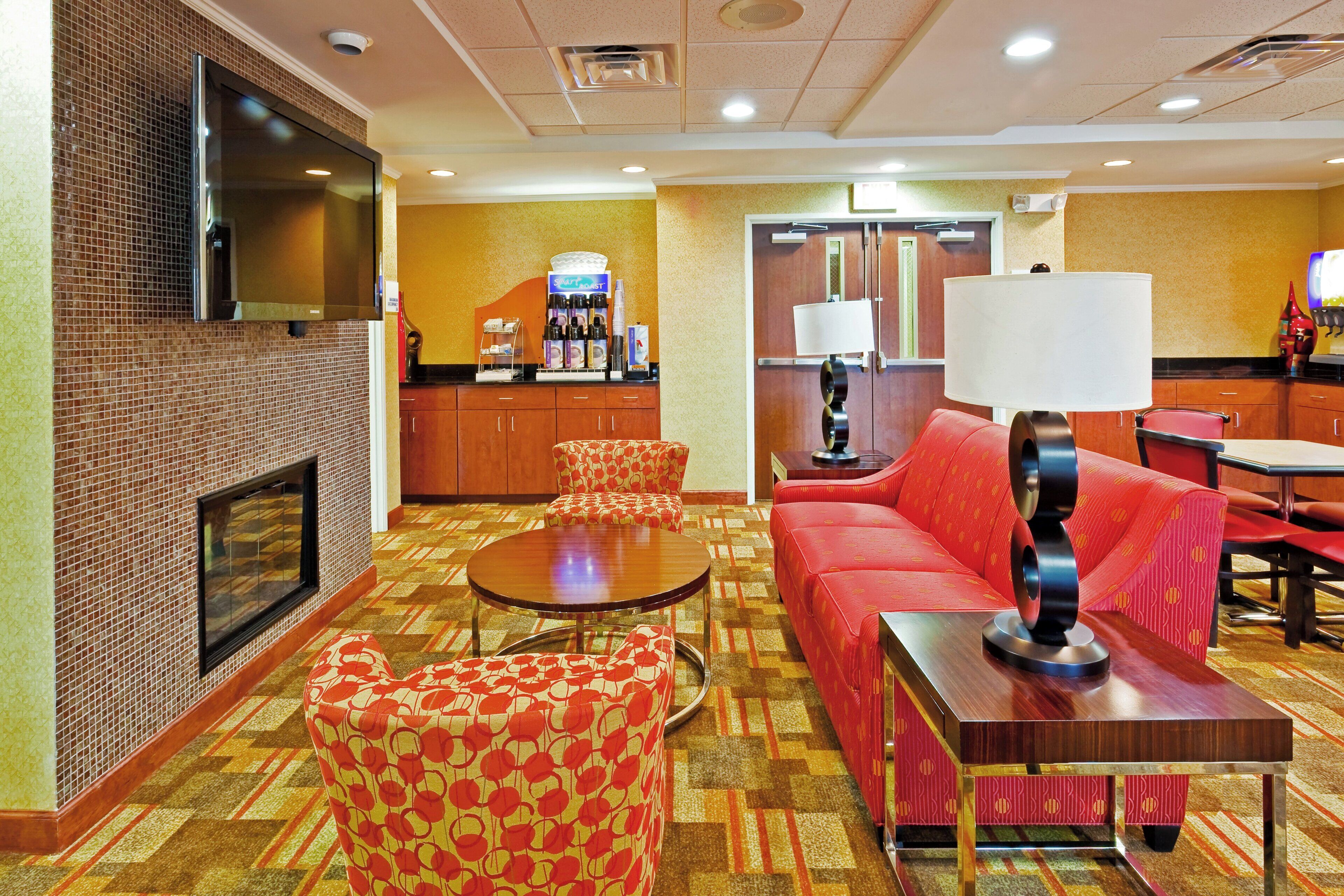 Un hall d'hôtel doté d'une cheminée, d'un espace salon et d'un coin café.