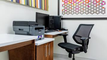 Un escritorio moderno con una computadora de escritorio, una impresora y una silla de oficina.