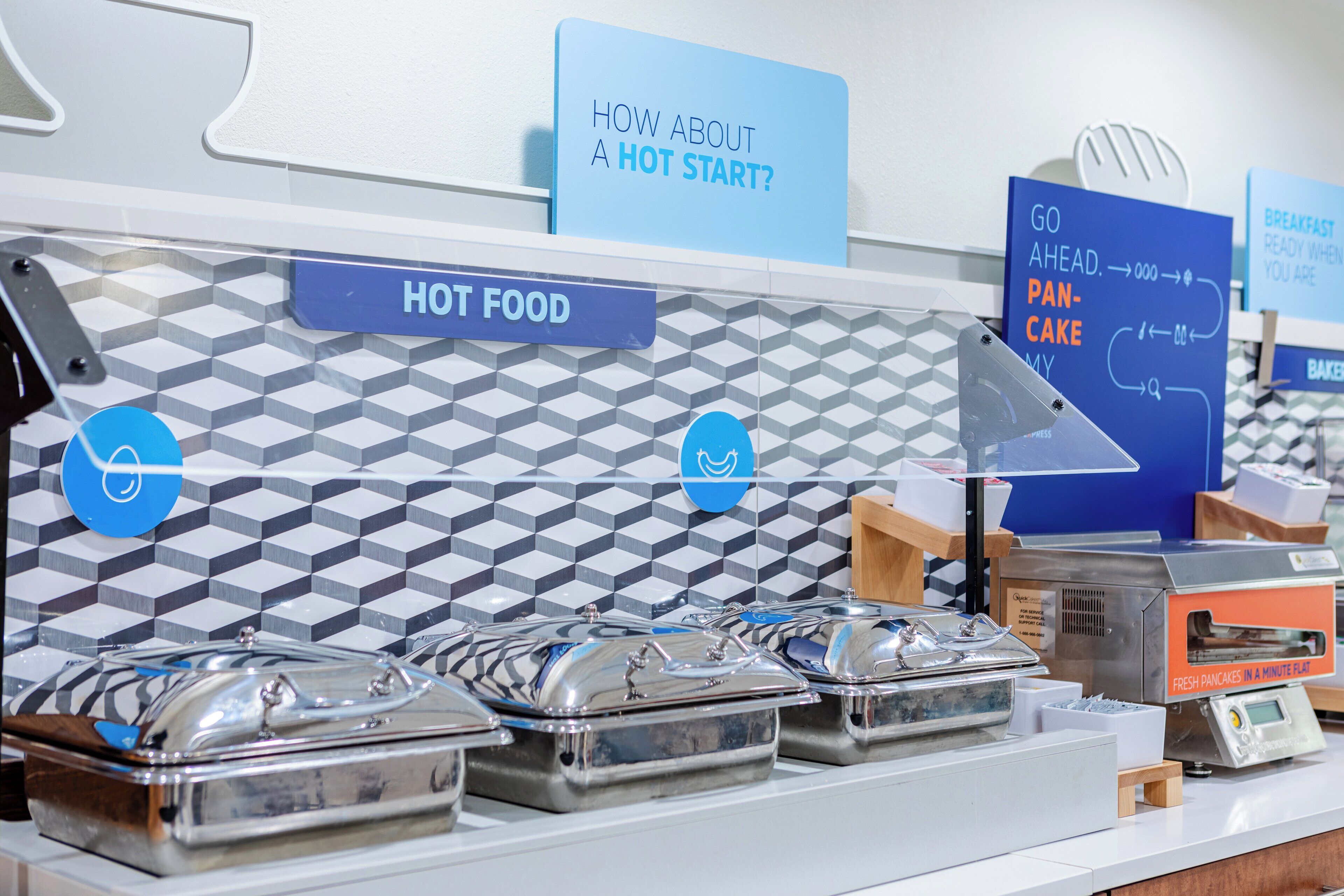 A buffet area with labeled signs for hot food and breakfast options.