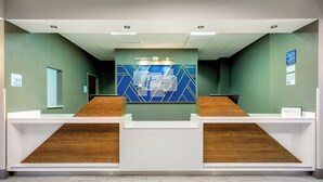A reception area with a modern design, featuring a reception desk, a waiting area, and a wall with geometric patterns. - Holiday Inn Express Hotel & Suites Ocoee East by IHG (Orlando)