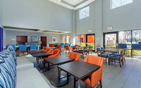 A spacious indoor area with multiple tables and chairs, a sofa, and a door marked "EXIT".