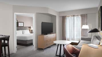 A hotel room with a bed, a TV, a desk, a chair, and a sofa.