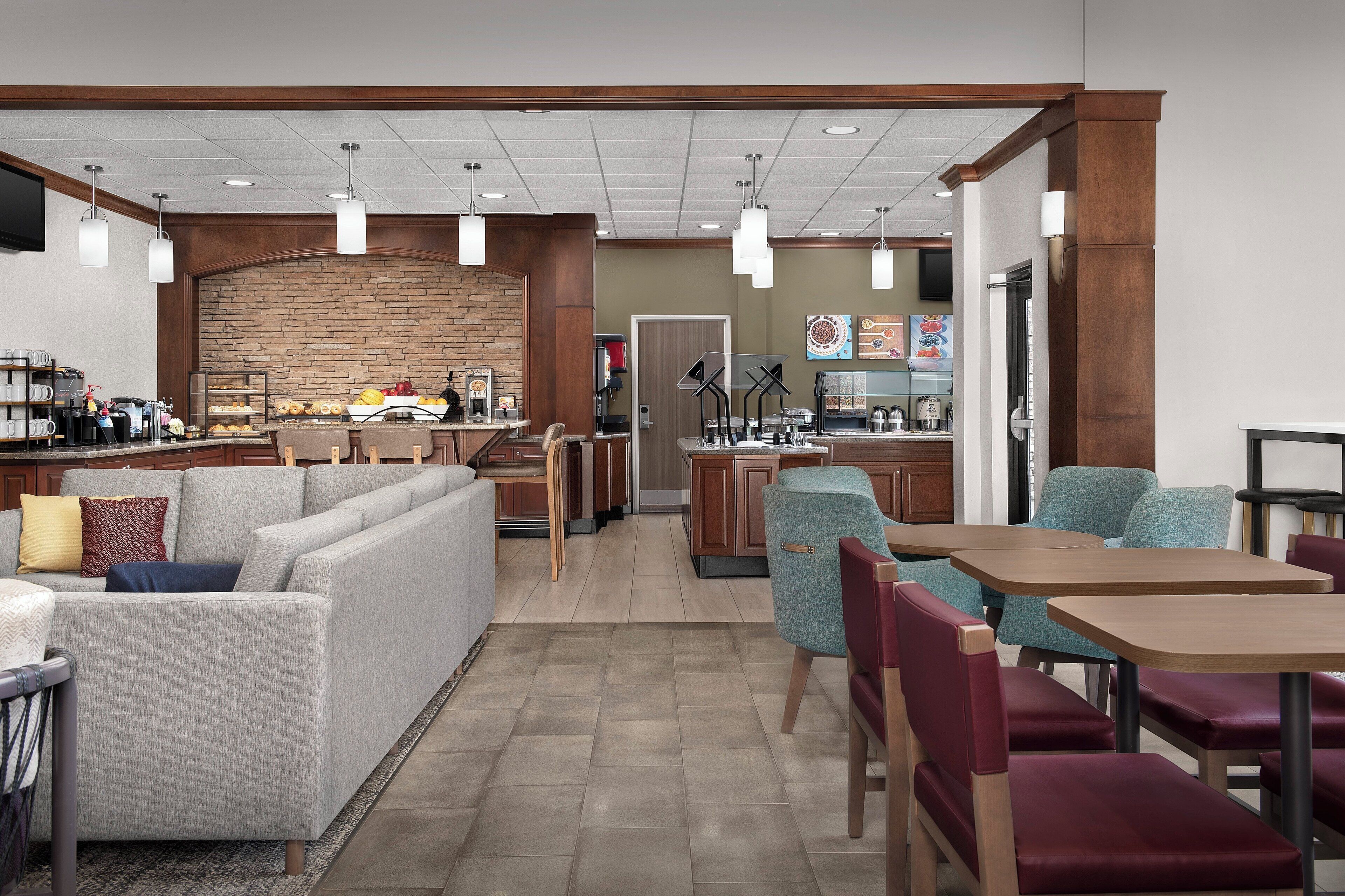 A hotel lobby with a seating area, a coffee bar, and a kitchen in the background.