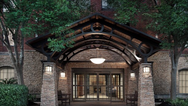 A building entrance with a stone facade, large glass doors, and a wooden archway. - Staybridge Suites Columbia by IHG (Columbia)