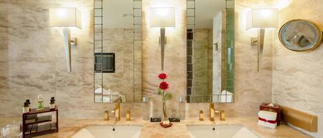 Un baño con dos lavamanos, un espejo y un florero con una rosa.