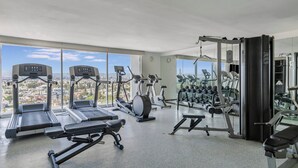 Ein Fitnessstudio mit Laufbändern, Crosstrainern, einer Hantelbank und einem Squat-Rack.