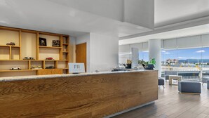 Ein moderner Empfangsbereich mit einem Holzbüro, offenen Regalen mit Dekoration und Blick auf die Stadt durch große Fenster.