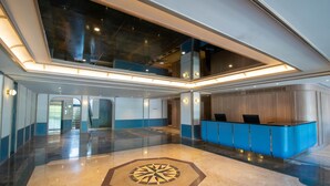 Un lobby amplio con una recepción, un diseño geométrico en el suelo y un techo alto con tragaluces.