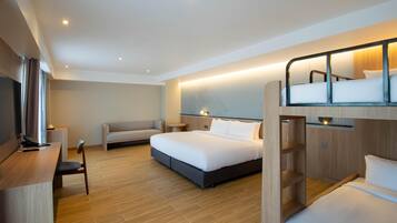 A modern hotel room with a bunk bed, a desk with a chair, a sofa, and a television.
