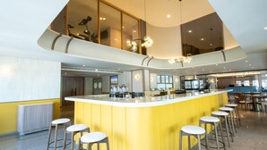Una cocina moderna con una isla central, taburetes de bar y un techo alto con una lámpara de techo original.