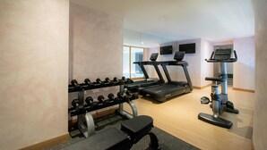 Un gimnasio con cintas de correr, pesas y una bicicleta estática.