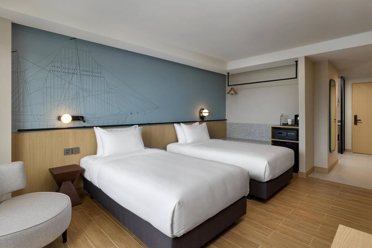 Hotelkamer met twee bedden, een zithoek, een muur met een ontwerp van een brug en een klein kitchenette.
