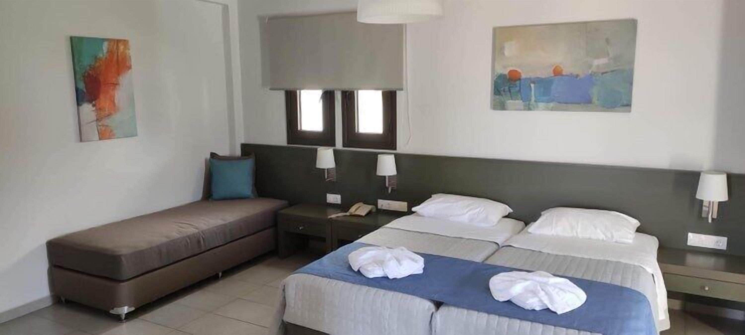 A hotel room with a bed, a sofa, a desk, and a nightstand.