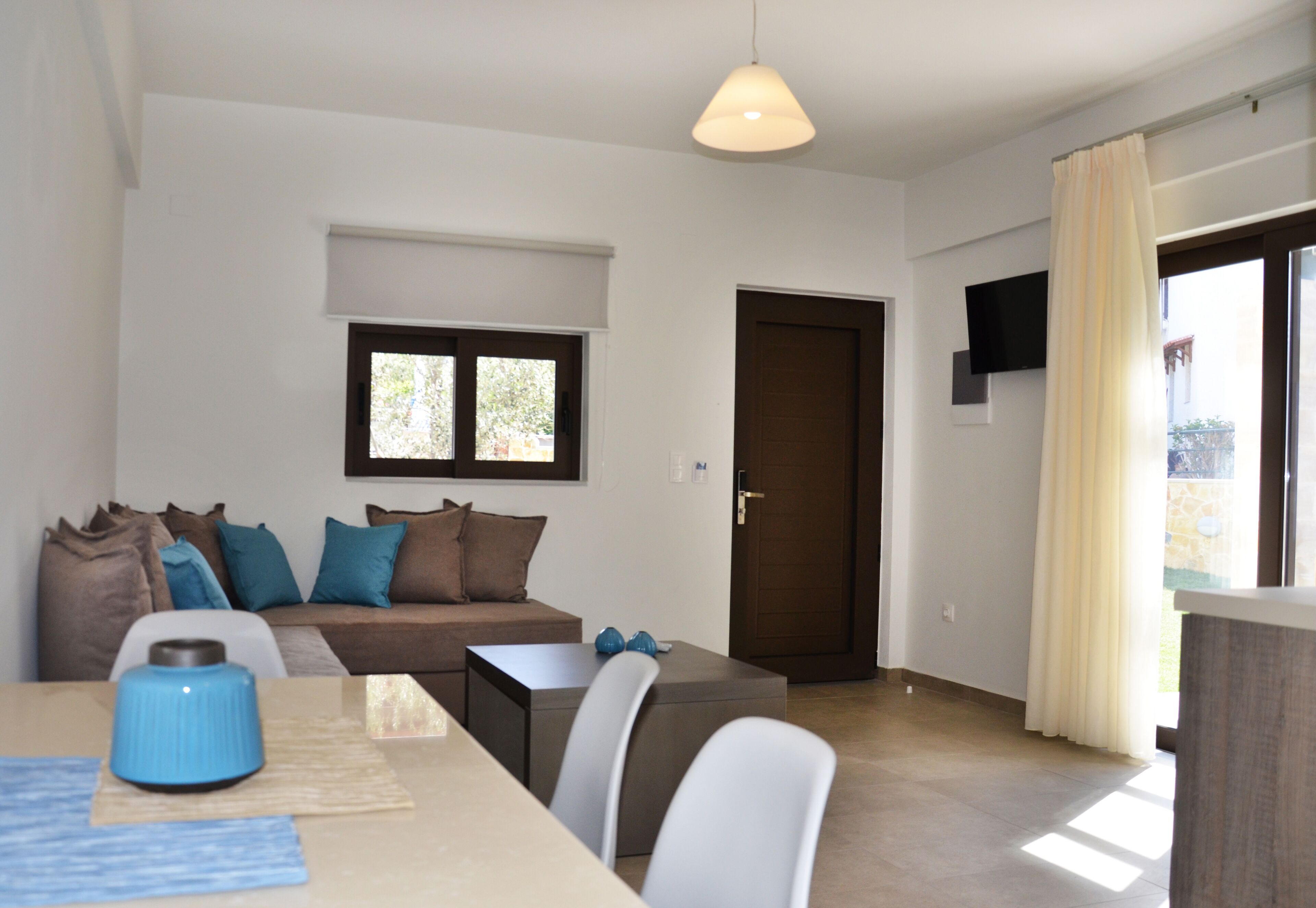 Een moderne woonkamer met een bank, een salontafel en een aan de muur bevestigde televisie.