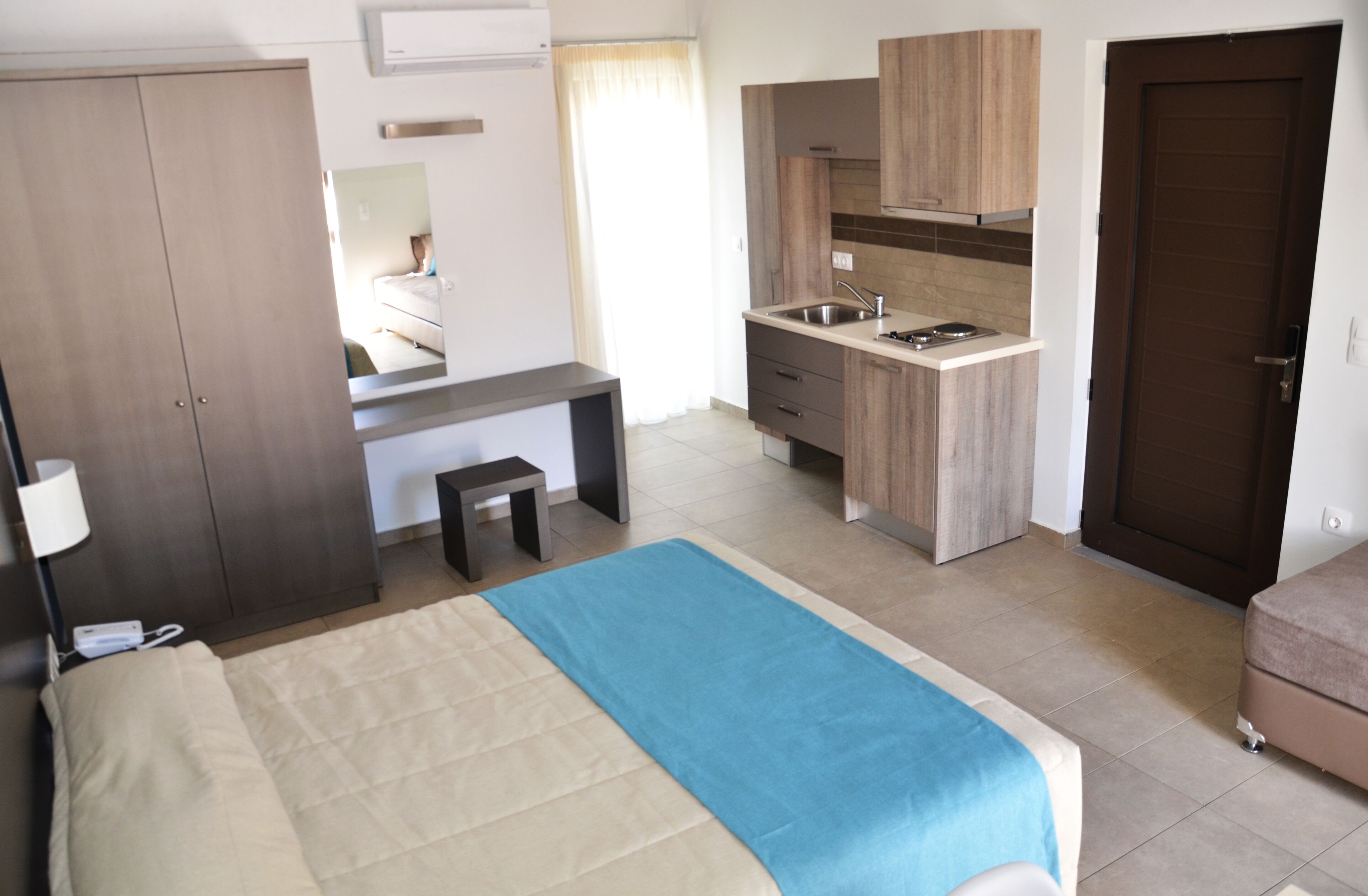 Une chambre d’hôtel comprenant un lit, un bureau, une kitchenette et une armoire.