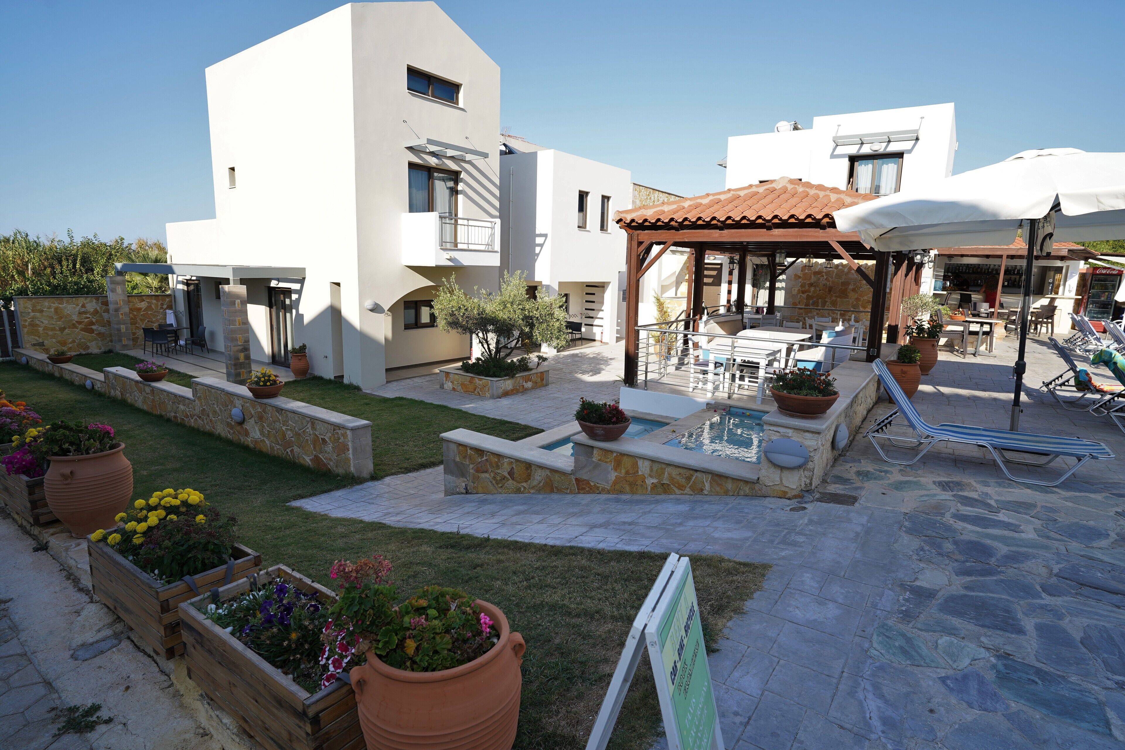 Un espace extérieur moderne, avec une terrasse, des jardinières en pierre, une piscine et des sièges d’extérieur.