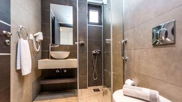 A modern bathroom with a glass shower enclosure, a sink with a mirror above it, and a toilet.
