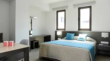 A hotel room with a bed, bedside tables, a desk, and a chair.