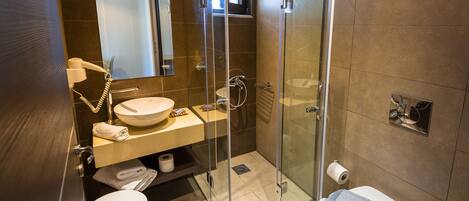 A modern bathroom with a glass-enclosed shower, a vanity with a sink and mirror, and two toilets.