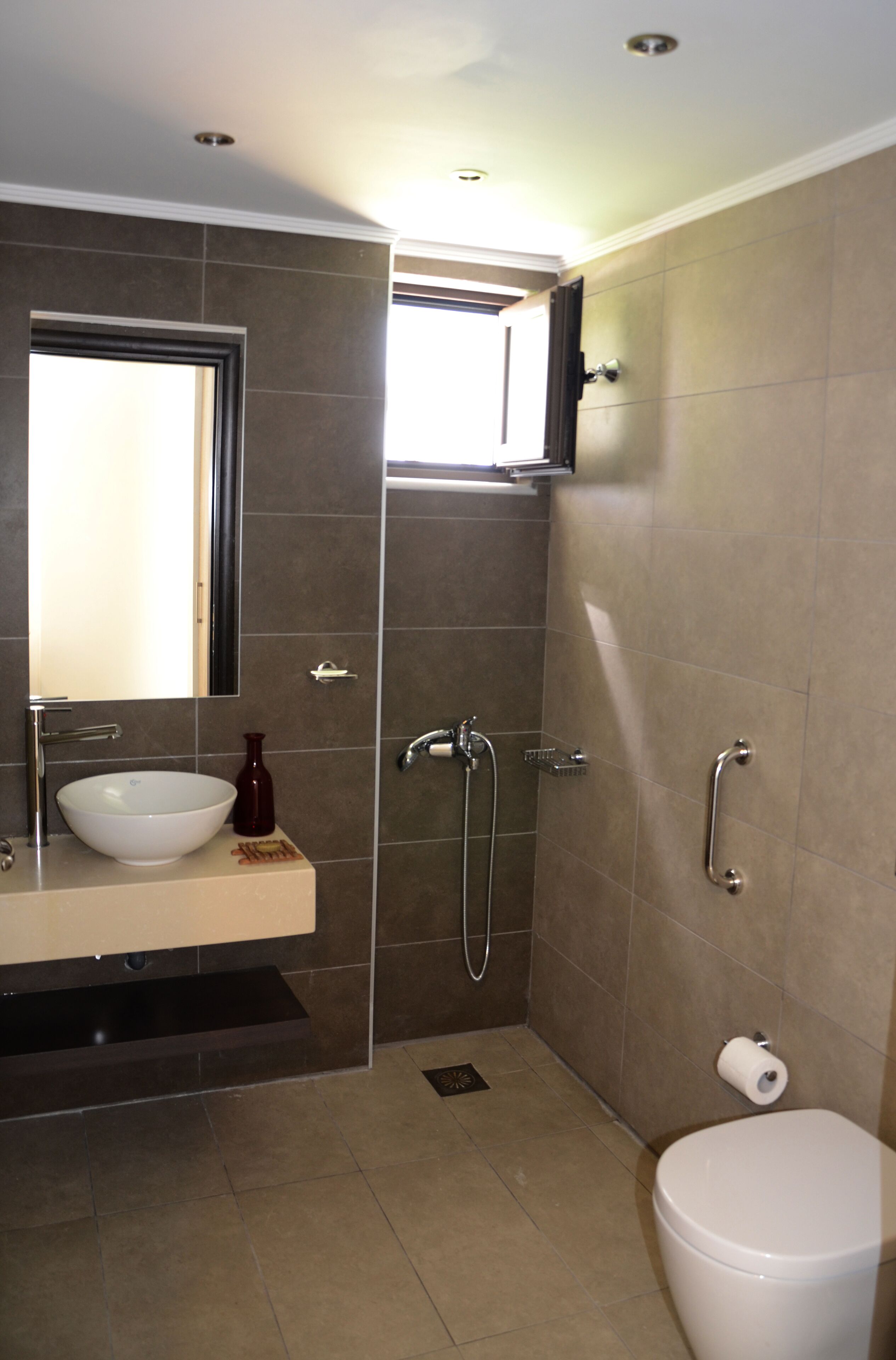 Un baño moderno con lavamanos, espejo y inodoro blancos.