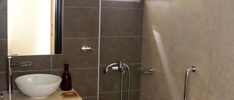 Un baño moderno con lavamanos, espejo y inodoro blancos.